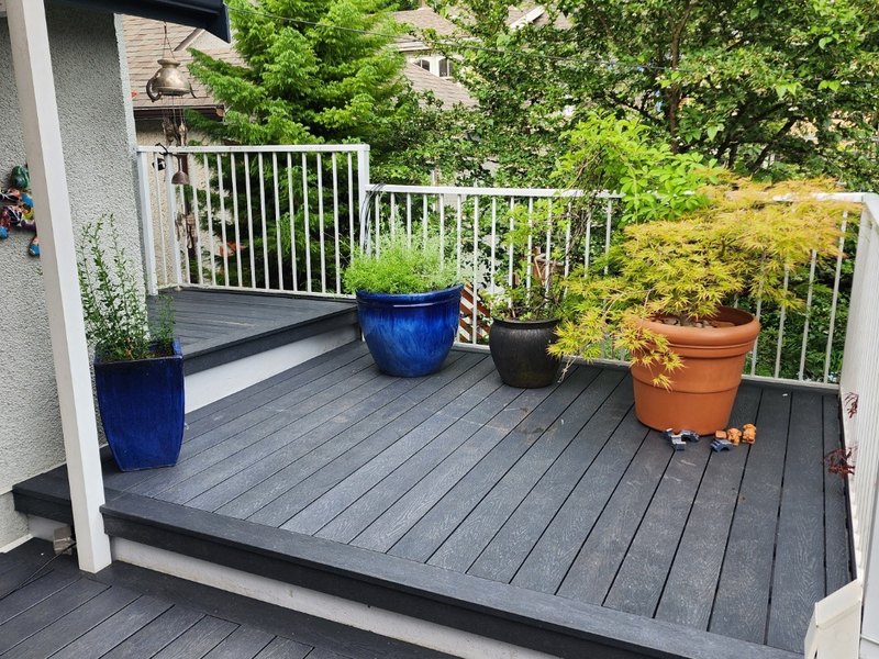 Backyard deck in dark grey recycled plastic lumber with potted plants along the rail