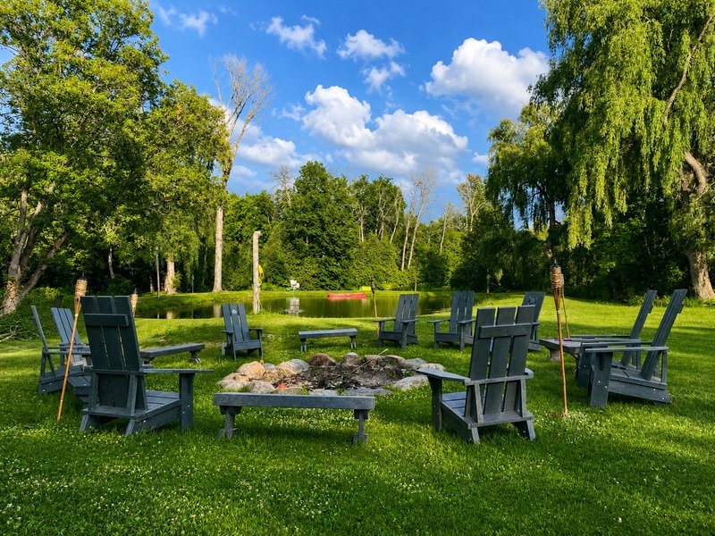 Recycled plastic Muskoka chairs set around a fire pit on a lawn