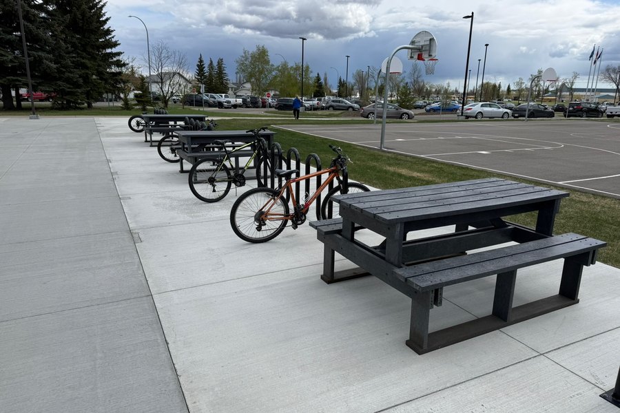 A recycled plastic picnic table beside bike racks in a public parking lot