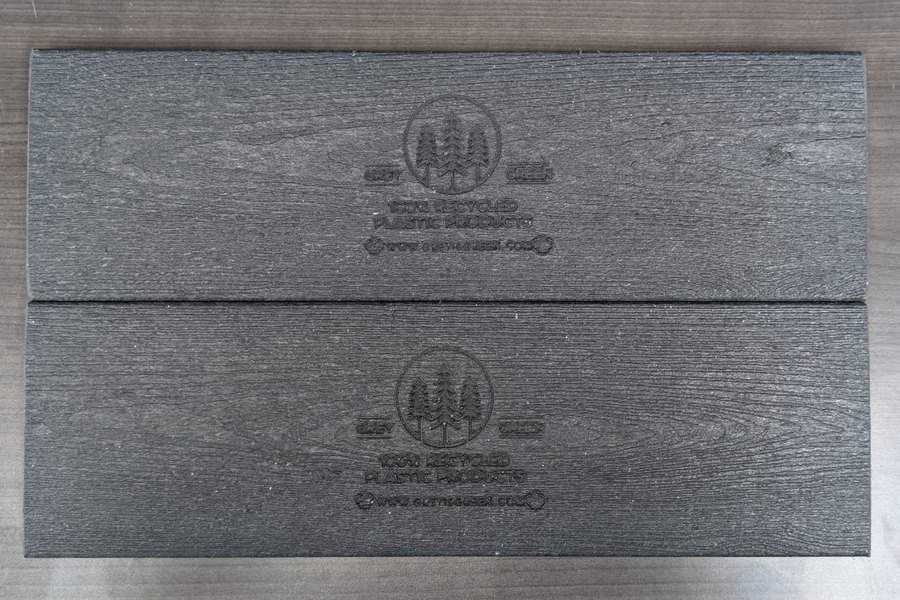 Two finished grey recycled plastic lumber boards showing the surface texture and the embossed Grey is Green mark